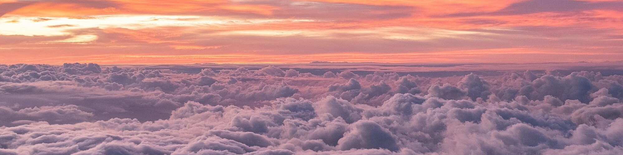 A stunning sunset over a sea of clouds, with silhouettes of people standing on a ridge.